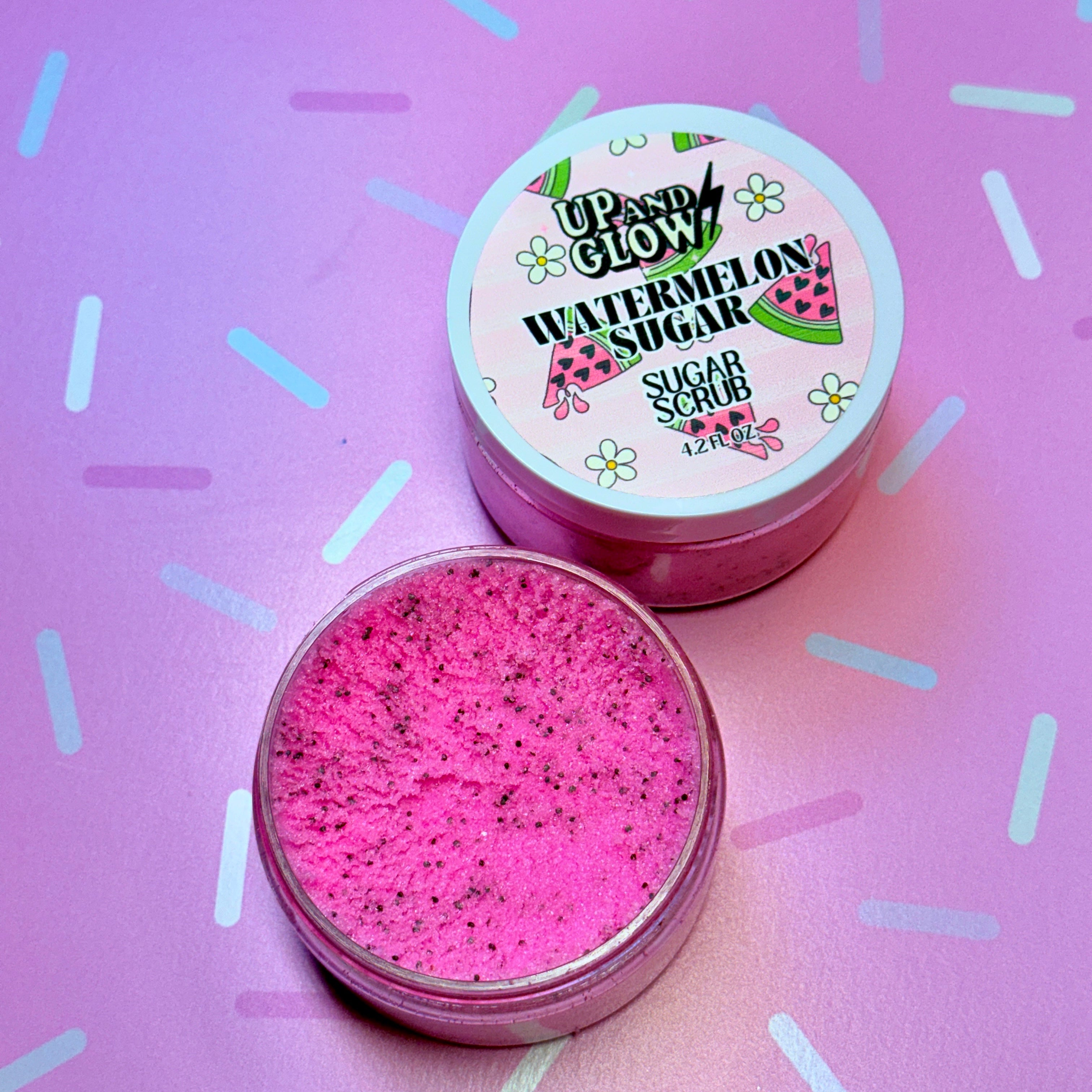 Pink sugar scrub with a labeled container on a pink background