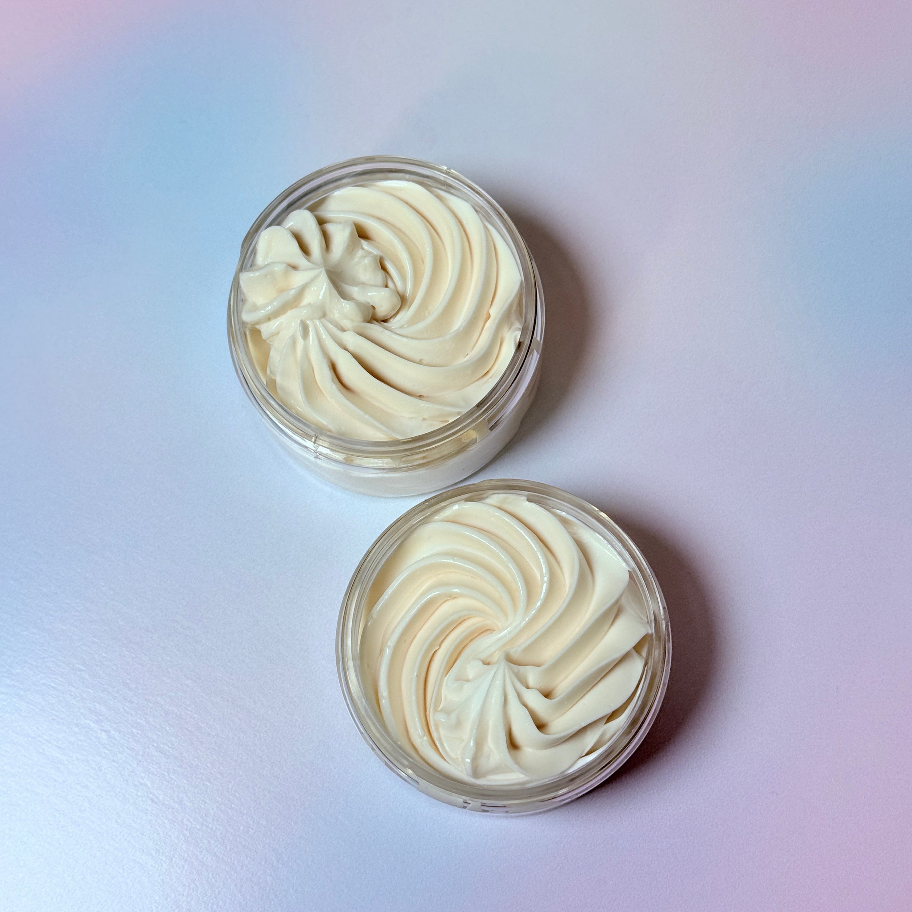 Two containers of white cream on a light purple background