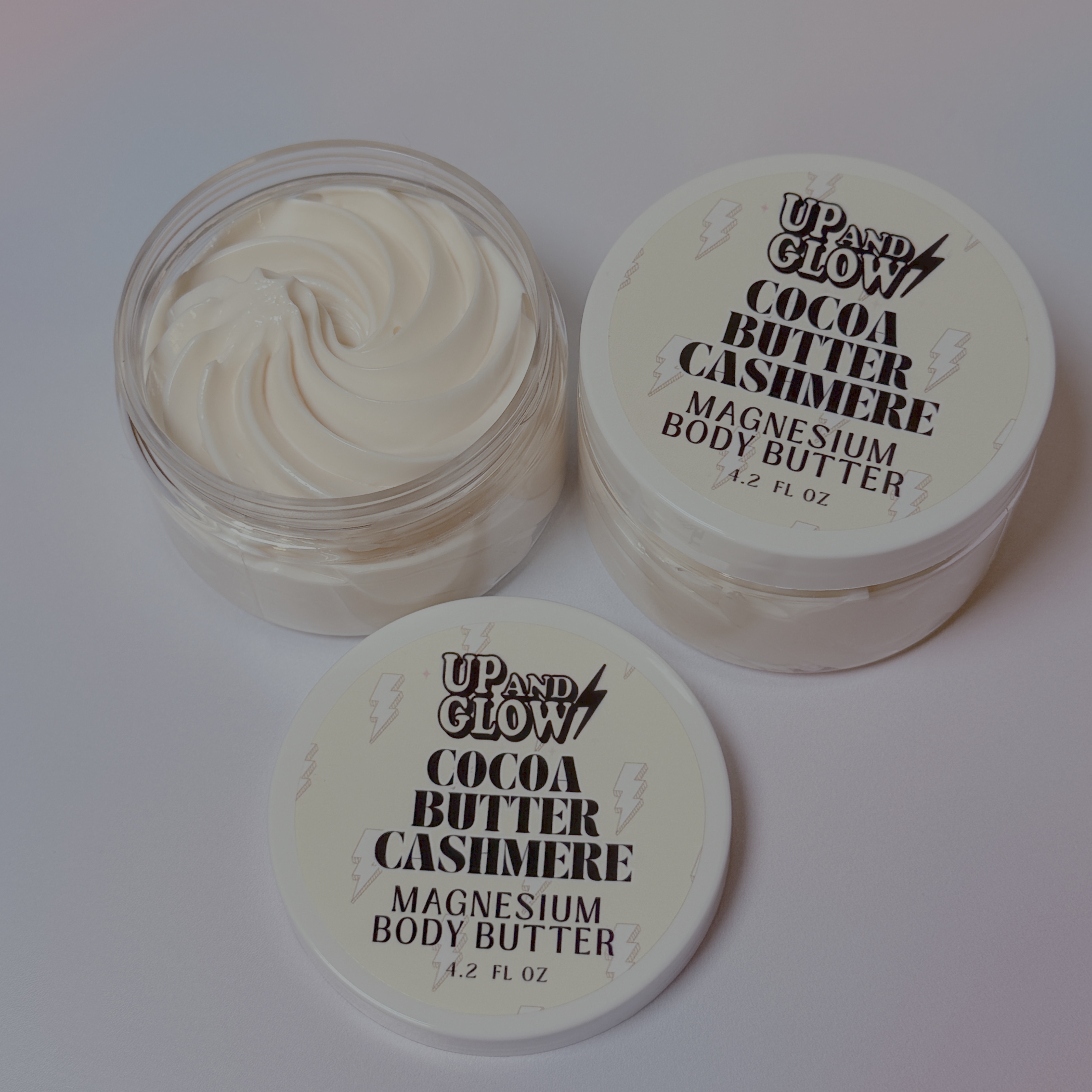 Up and Glow Cocoa Butter Cashmere magnesium body butter with lid on a white background