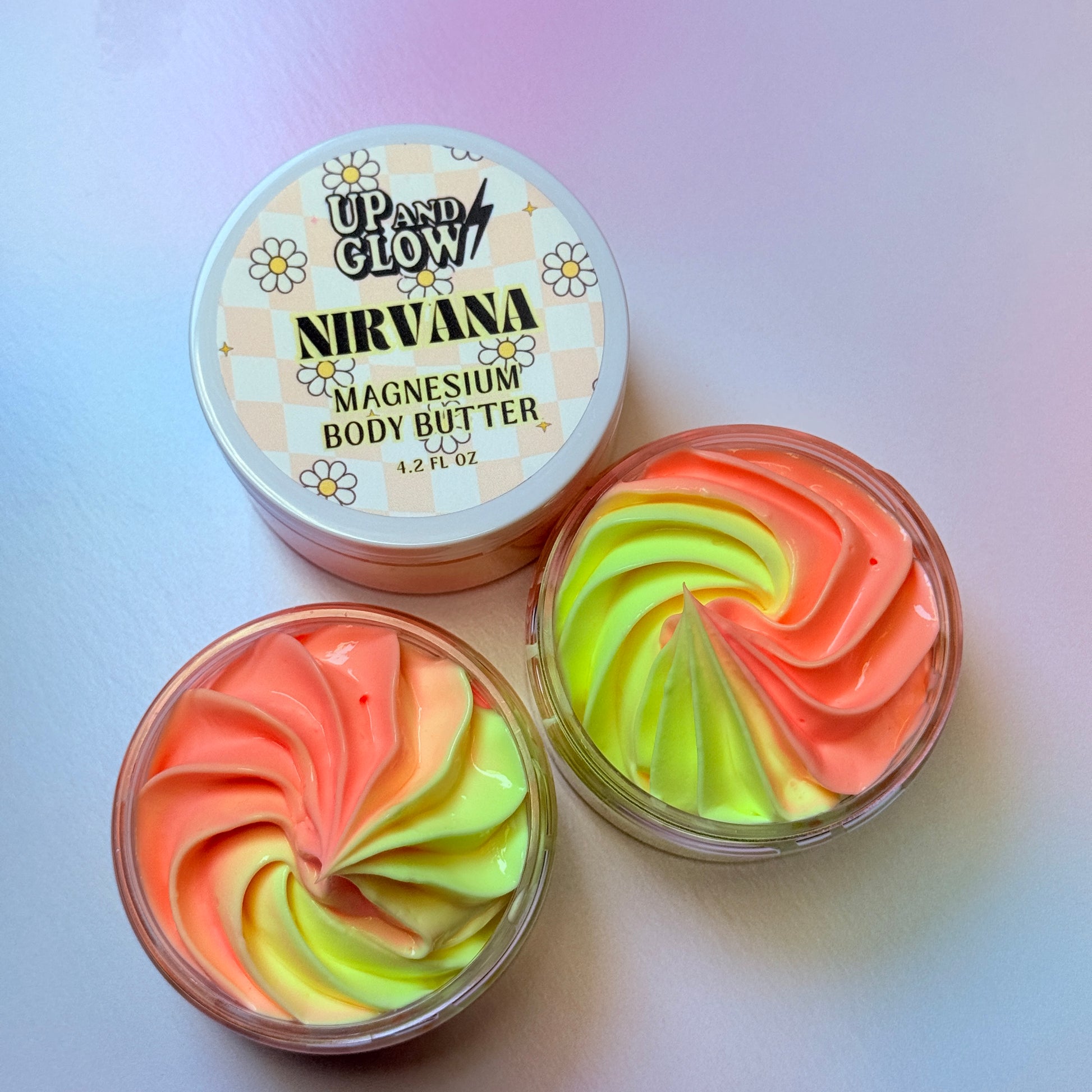 Two containers of colorful magnesium body butter with 'Up and Glow' branding on a light pink . background. Nature colors, dye free skincare. magnesium for better sleep
