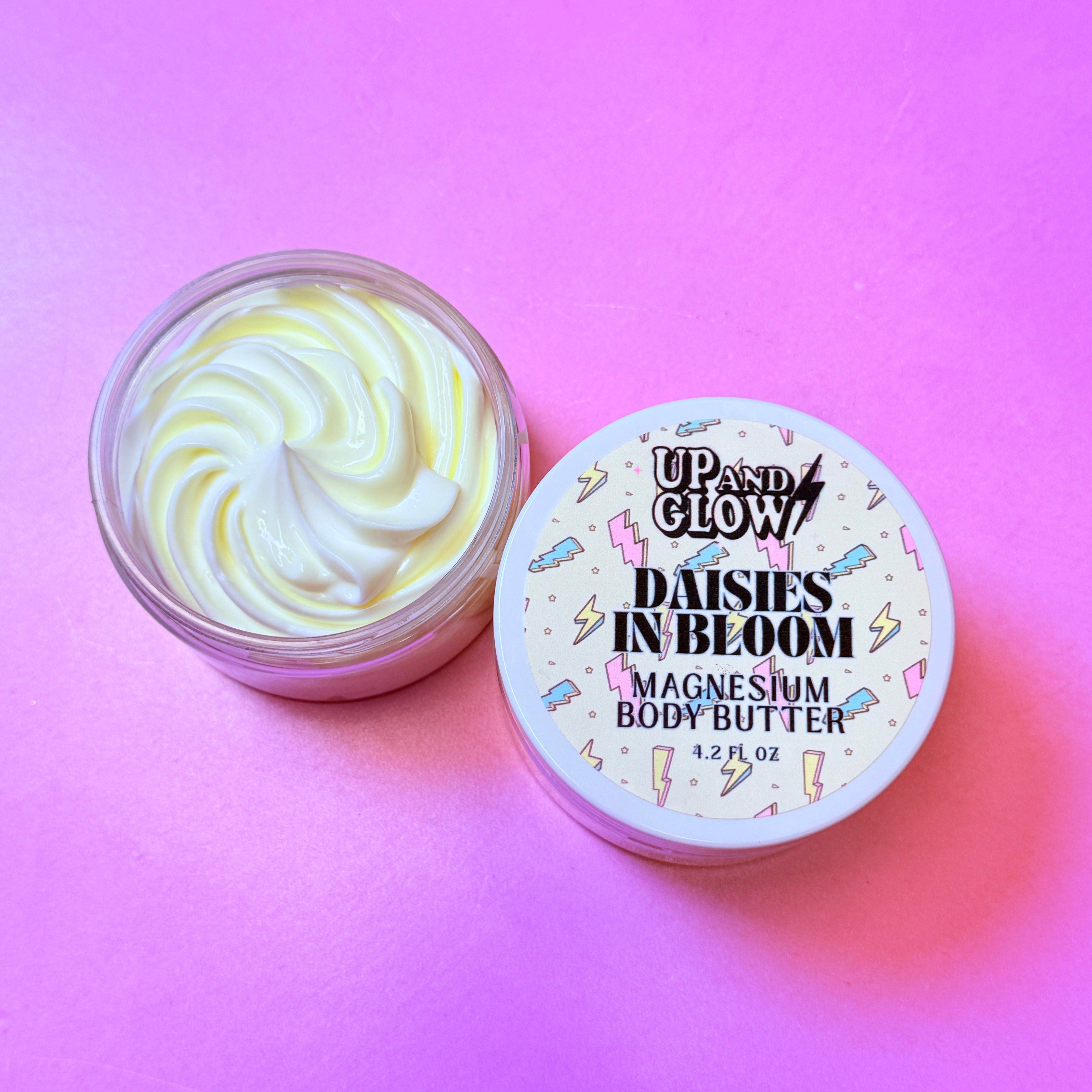Open jar of magnesium body butter with a pink background