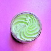 Jar of green and white swirled cream on a pink background. Body Butter for deep hydration and repair