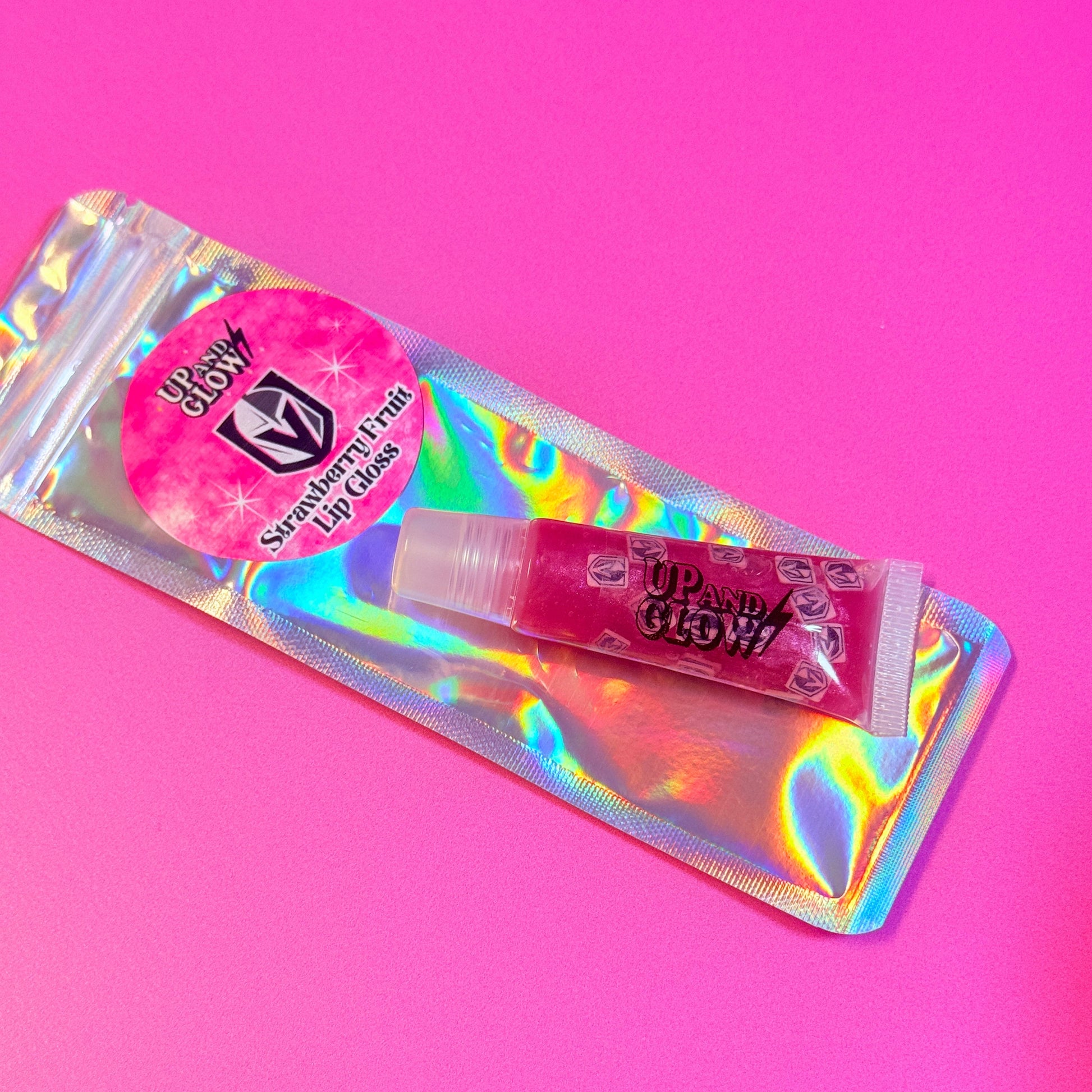Pink lip gloss with a holographic tube on a pink background